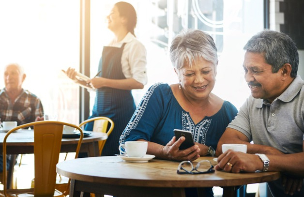 Happy couple uses Wi-Fi in a cafe content they're following 8 rules for savvy cybersecurity.