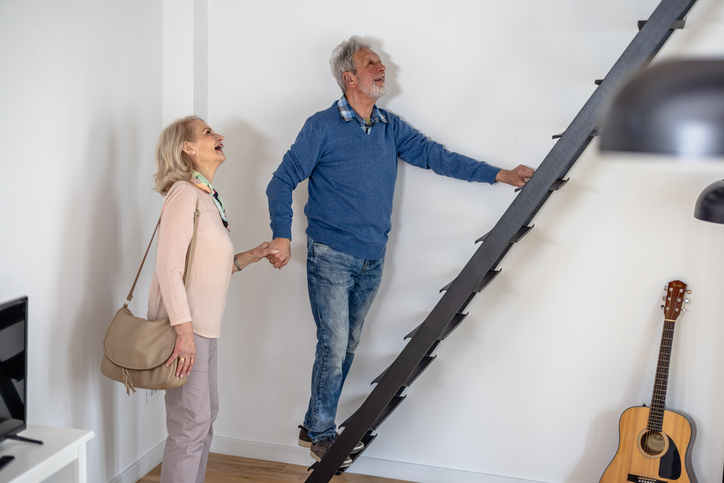 Older couple looks up ladder connecting their upper level in new home they could afford by investing in CD ladder aka certificates, time deposits, certificates of deposit. 