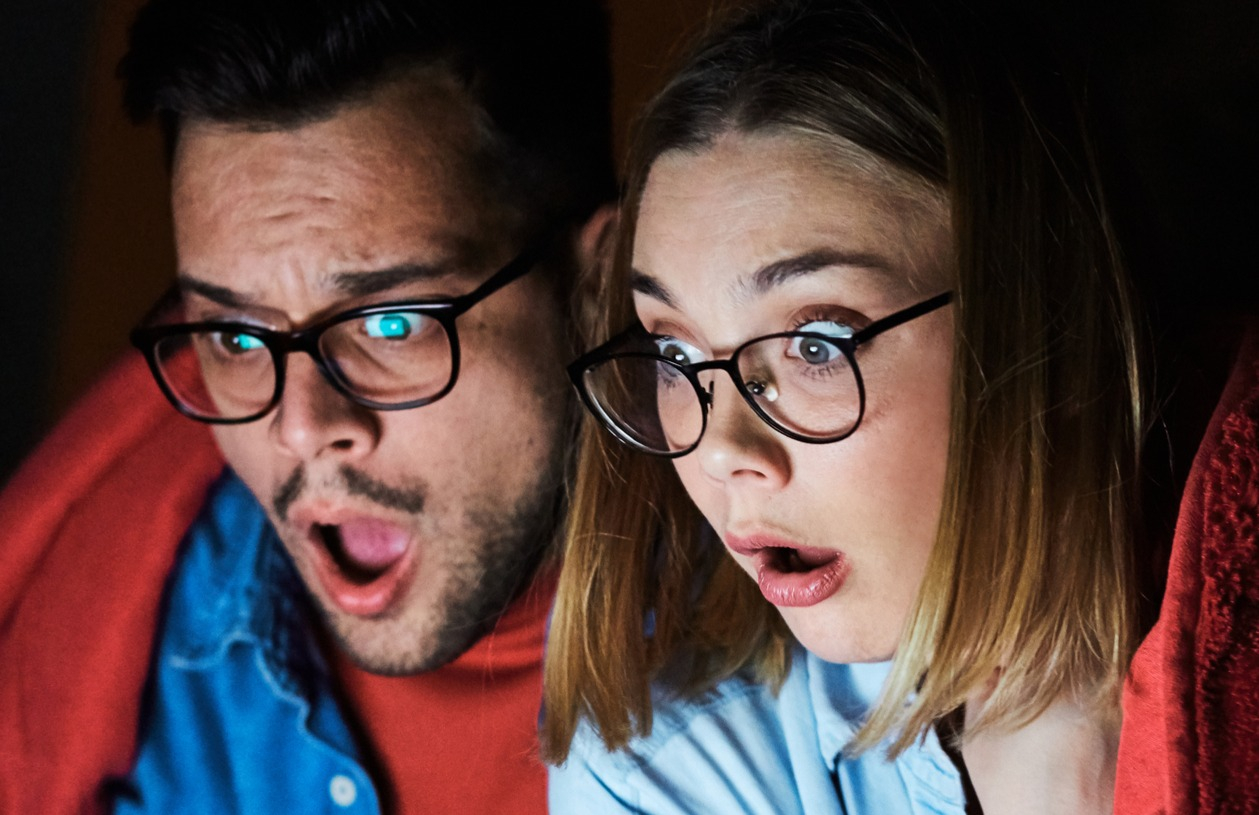 Couple watches scary movie on their laptop on Halloween.