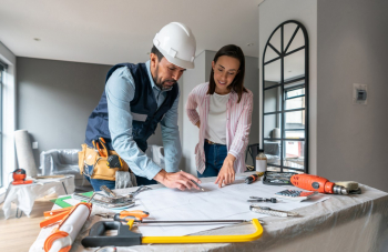 A woman discusses her home improvement plan with a contractor inside her home