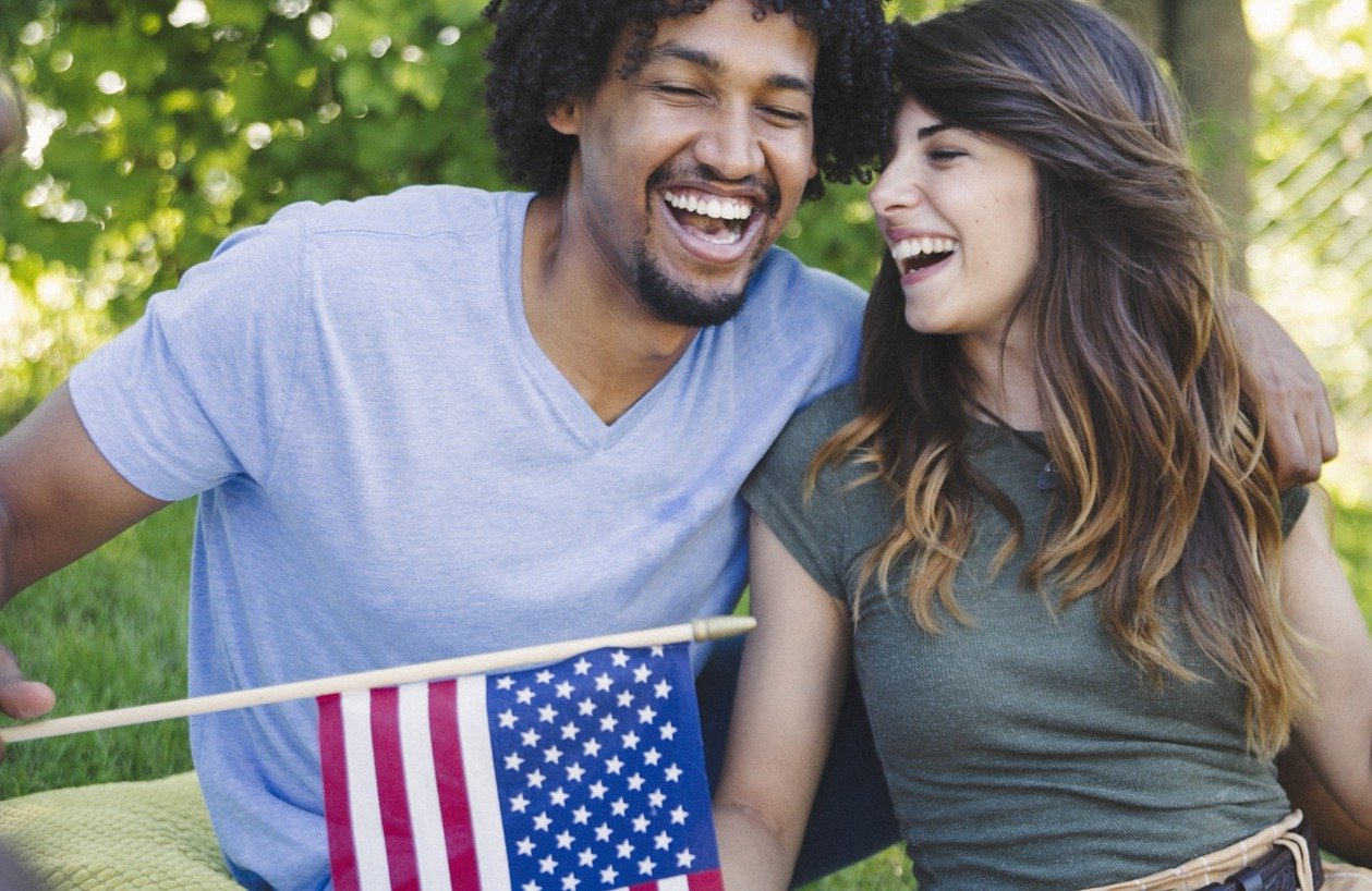Young picnicking couple waves American flag on America's 25oth birthday.