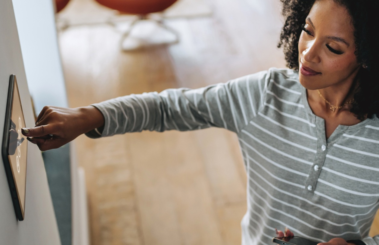 Woman taps her home's thermostat while considering how much equity to tap into for a home equity line of credit (HELOC).