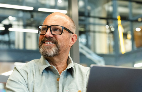 Worker approaching retirement age uses AI on his laptop on the job.