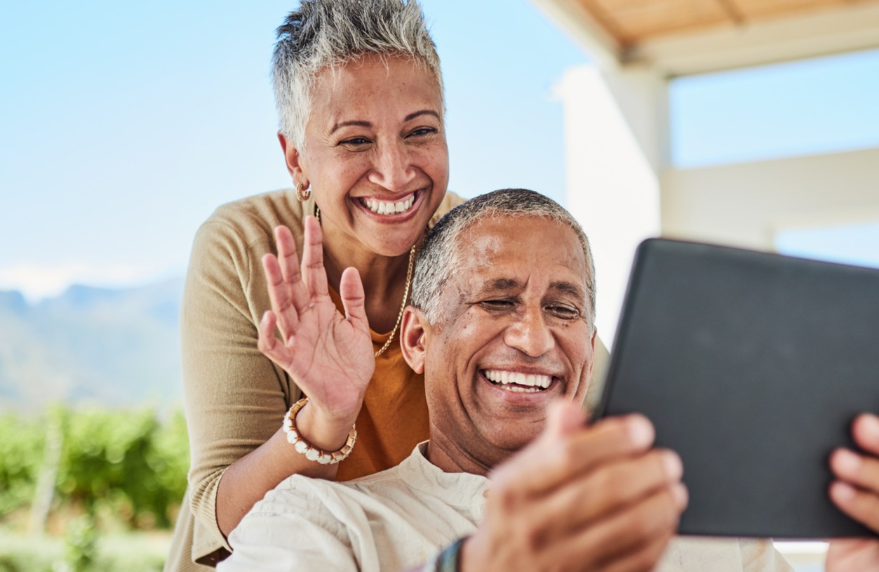 Retired couple review their Social Security and Medicare benefits on their tablet on their back patio. 
