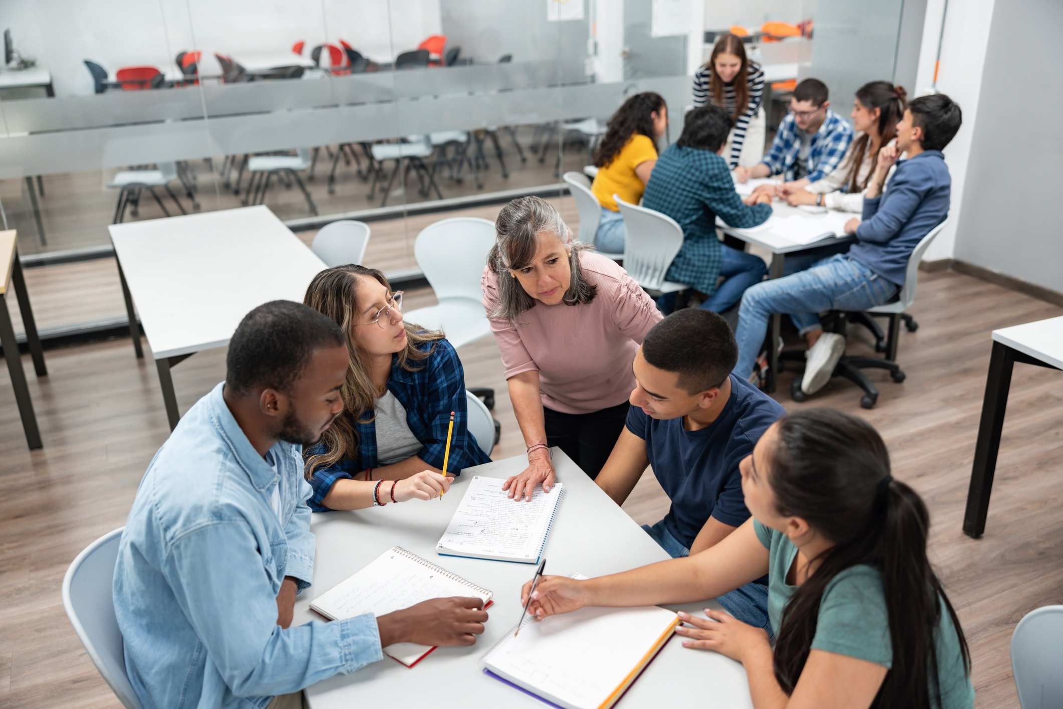 Group of teenage students listen to teacher in school's library.