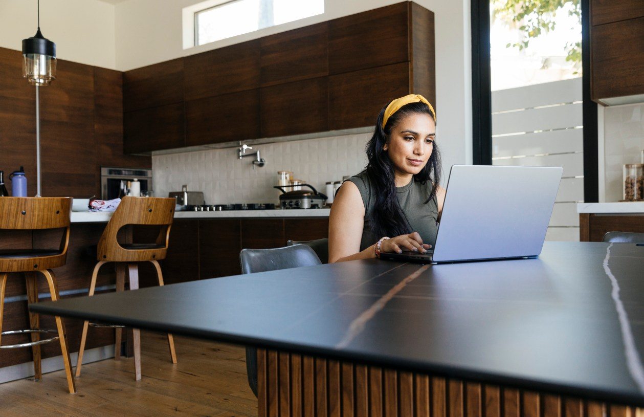 Woman sitting on her laptop at a kitchen table