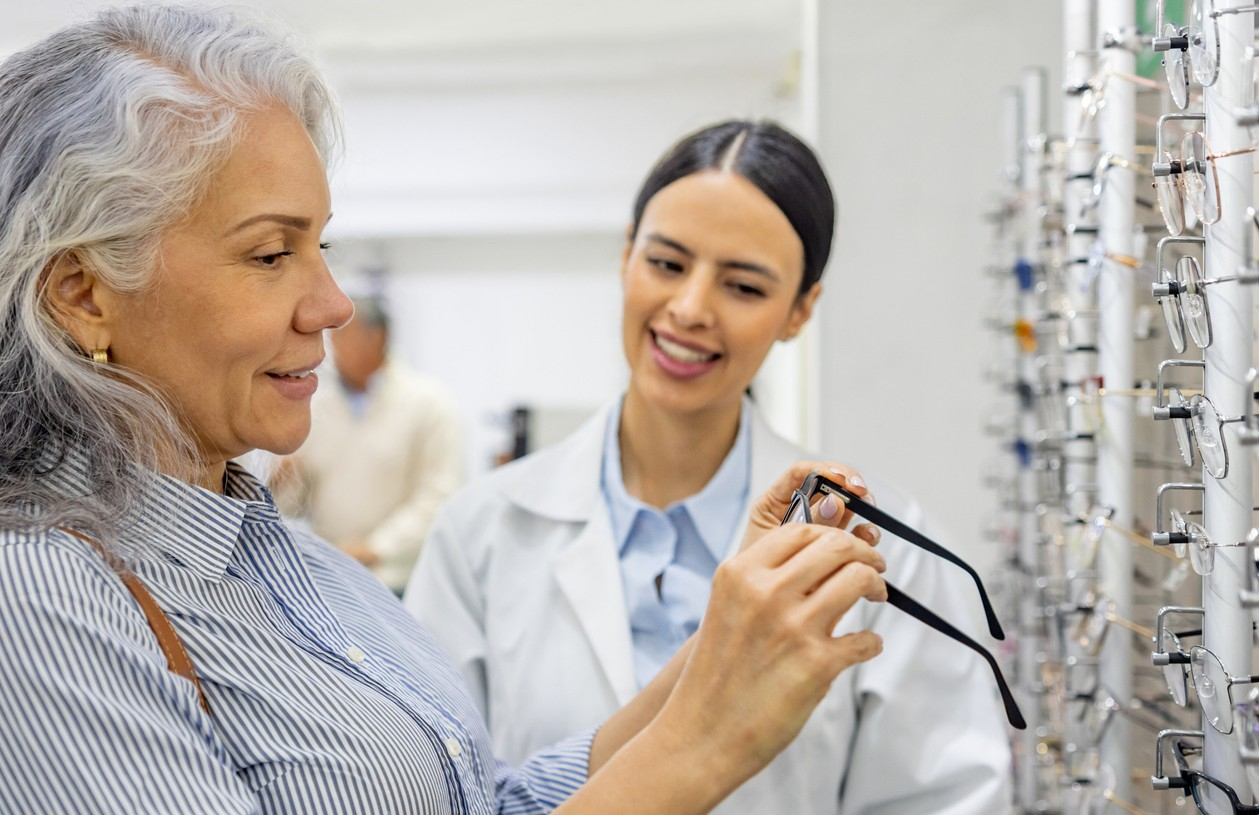A middle-aged woman works with an optician to select eyeglasses using funds from her health savings account (HSA) 