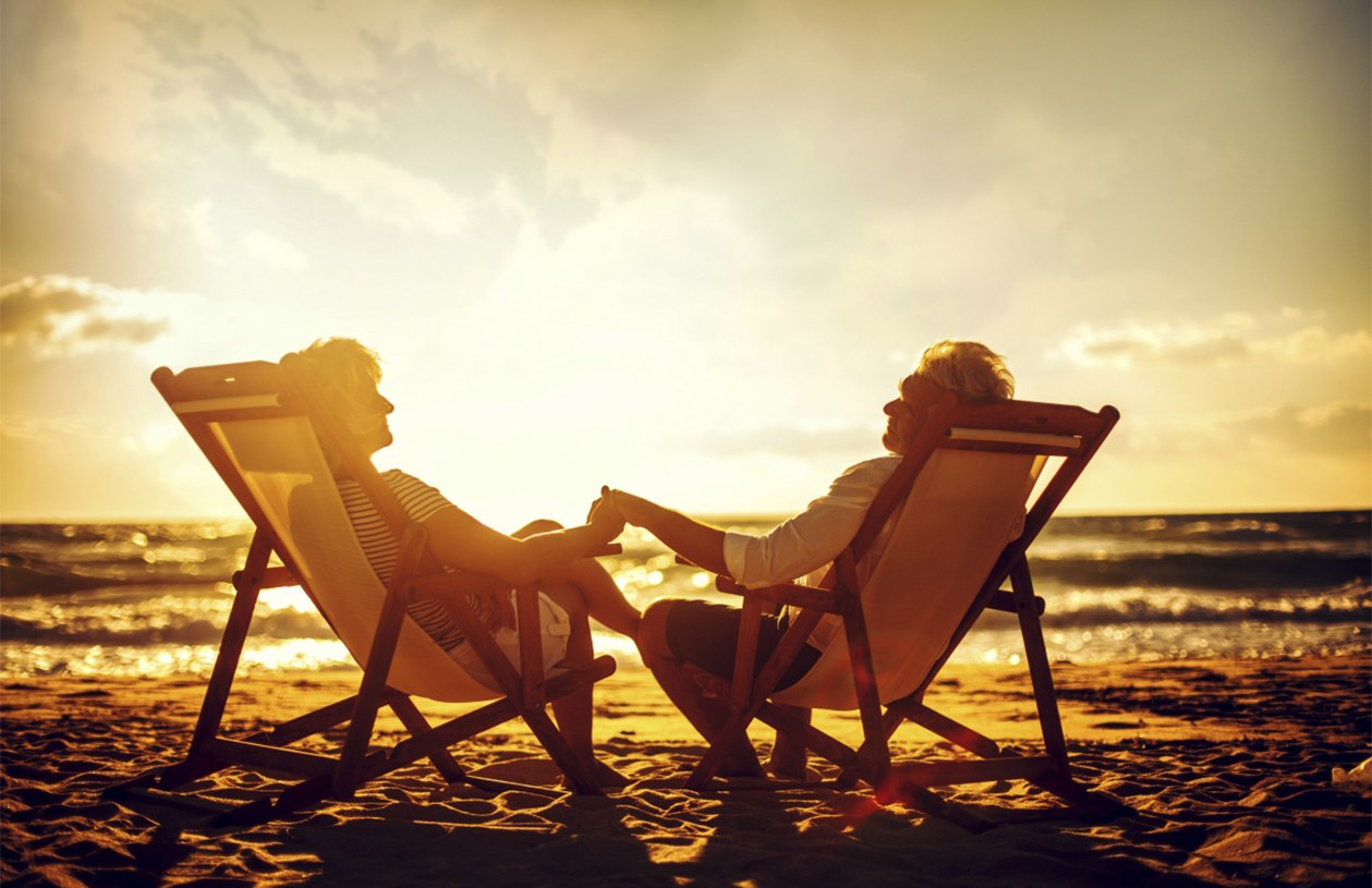 couple holding hands  at sunset sitting on the beach
