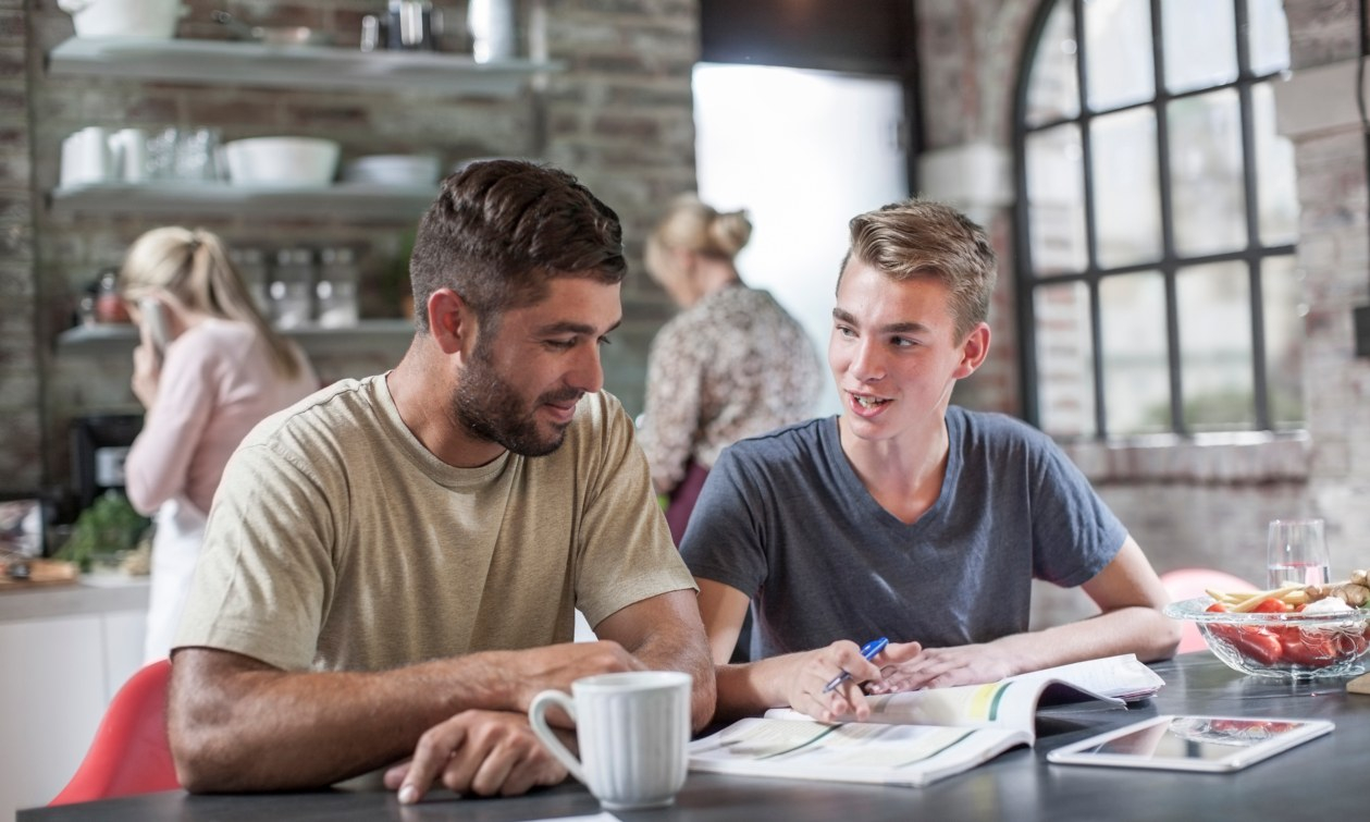 A father and son discuss student loan options over homework.