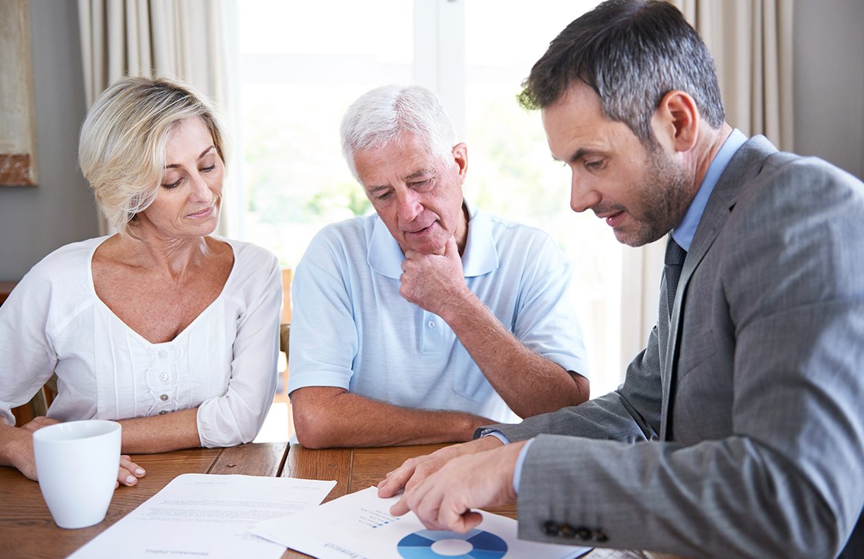 couple meeting with their financial advisor sitting at a dining room table

